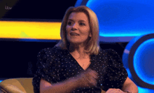 a woman in a polka dot dress is sitting in front of a tv screen that says itv on it