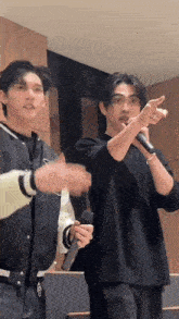 a couple of men are standing next to each other holding microphones and pointing at something .