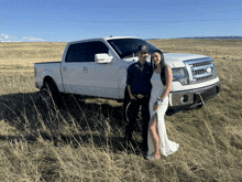 a man and a woman pose in front of a white truck