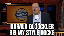 a man in a suit is standing in front of a sign that says `` harald gloocker bei my style rocks '' .