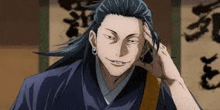 a man with long hair and earrings is smiling and holding his hand to his forehead .