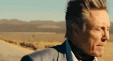 a man in a suit and tie is standing in a desert