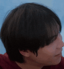 a close up of a young man 's face with a red shirt on