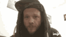 a man with a beard and nose ring is wearing a hoodie and hat