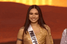 a woman wearing a sash that says philippine on it is smiling .