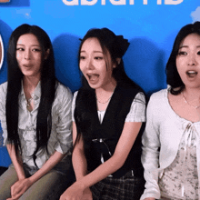 three women are sitting in front of a blue wall that says ' ui ' on it