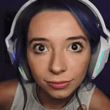 a woman with blue hair is wearing headphones and making a funny face