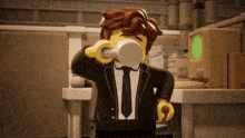 a lego figure in a suit and tie is drinking from a cup