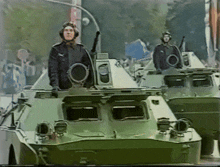 two soldiers are standing on top of a military vehicle