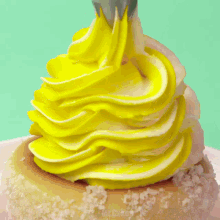 a close up of a person 's hand decorating a dessert with yellow frosting