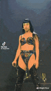 a woman in a bra and thigh high boots is dancing on a stage in front of a crowd .