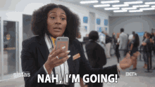 a woman holding a cell phone with the words nah i 'm going