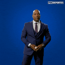 a man in a suit and tie is smiling in front of a blue background that says fox deportes on it