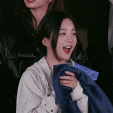 a woman with her mouth open is holding a blue scarf