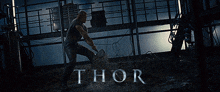 a movie poster for thor shows a man holding a hammer in a dark room