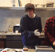 a man in a purple sweater is standing in a kitchen with a toaster
