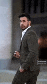 a man in a suit holding a cell phone in his hand