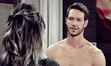 a shirtless man is standing next to a woman in front of a mirror and smiling .