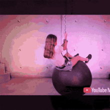 a woman is chained to a large black ball with a youtube tv logo in the corner