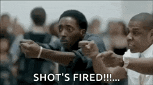 a man is pointing a gun at another man while another man says `` shot 's fired '' .