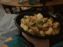 a person is holding a bowl of food with a spoon