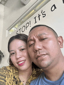 a man and woman are posing in front of a sign that says " stop it 's a "