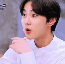 a young man in a white shirt is making a funny face