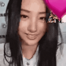 a close up of a woman 's face with a pink heart balloon in the background .