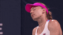a woman wearing a pink visor and a white tank top