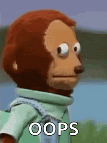 a stuffed monkey is making a funny face with the words oops written on it .