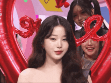 a woman stands in front of a heart shaped balloon with the word love on it