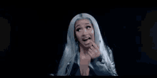 a woman with long blue hair is smiling and making a face .