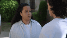 a woman in a striped shirt is talking to a man in a blue shirt