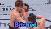 two men are fighting in a ring with the word bitches in blue