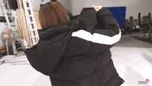 a woman is wearing a black jacket with a white stripe on the sleeves and the words happybook entertainment on the bottom right