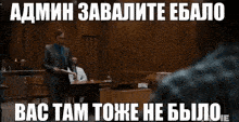 a man in a suit and tie stands at a podium in a courtroom with a foreign language caption above him