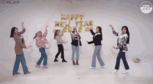 a group of women dancing in front of a wall that says happy new year 2022