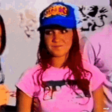 a woman wearing a blue hat and a pink shirt with a gun on it says rbd gif