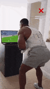 a man is squatting in front of a television with a red x on it