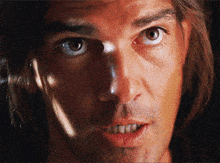 a close up of a man 's face with long hair