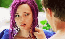 a woman with purple hair is being touched by a man in a blue jacket .