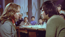 a man and a woman looking at each other in front of a crowd