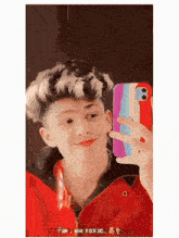 a young man taking a picture of himself in a mirror with a rainbow phone case