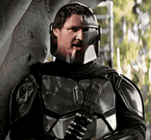 a man in armor is leaning against a tree holding a gun