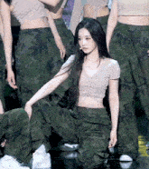 a woman in a crop top and camo pants kneeling down