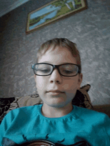 a young boy wearing glasses and a blue shirt is sitting on a couch