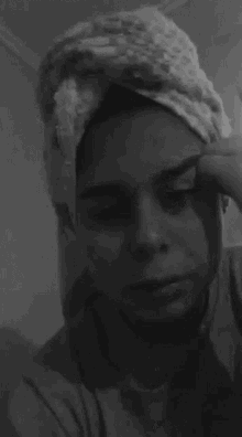 a woman with a towel wrapped around her head is applying makeup .