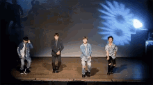 a group of young men are dancing on a stage in front of a flower projection