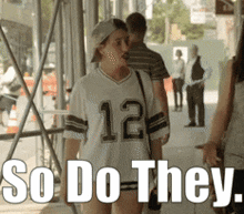 a woman wearing a jersey with the number 12 on it is walking down the street