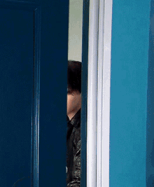 a person peeking out of a blue door with a white trim